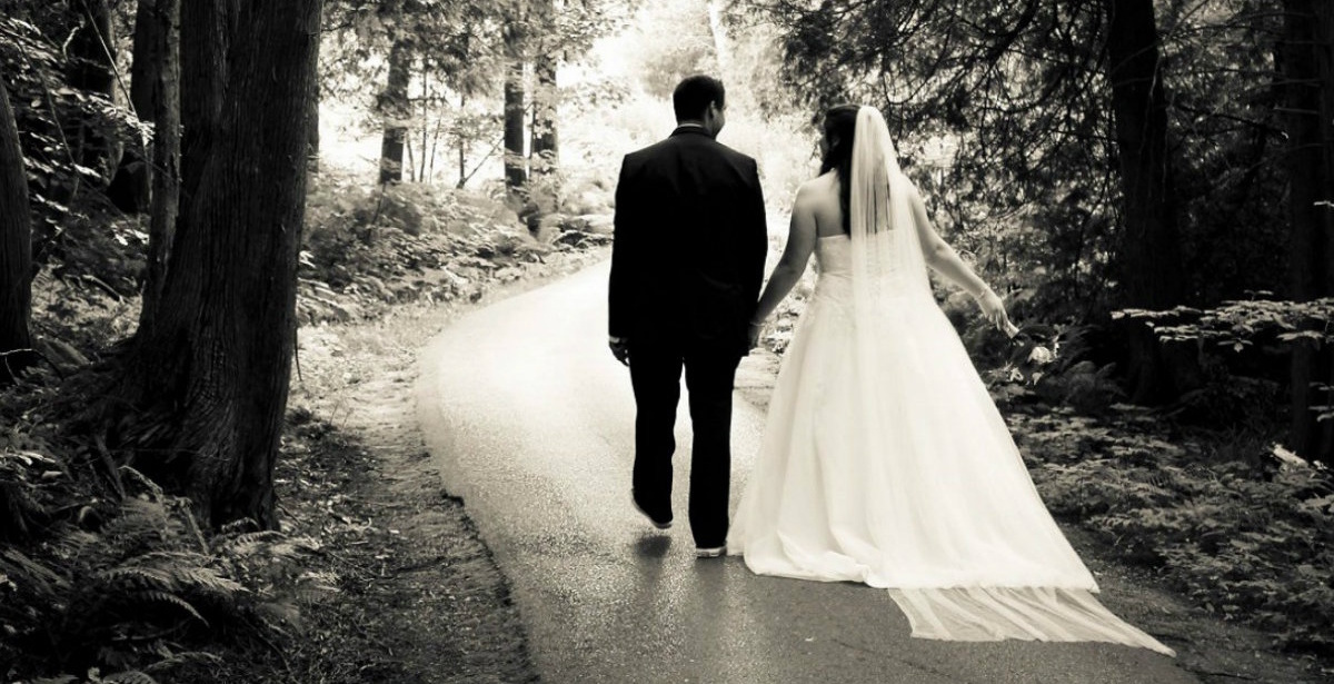 A male and female couple poses on their wedding day in a park